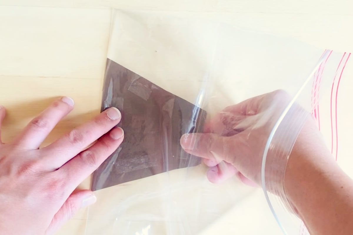 place a brown paper volcano mountain inside a ziplock bag.