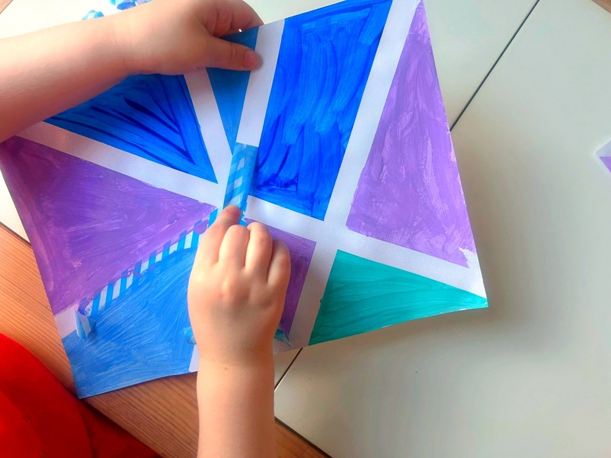 removing the tape to reveal the painting